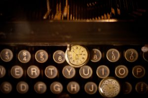 Writing groups: an image of a typewriter keyboard with two old-fashioned timepieces on the keys. 