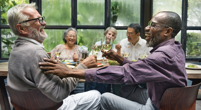 How to write dialogue in a true story. Image of a group of mature friends having dinner, laughing and engaging in lively conversation.